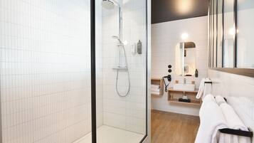 Une salle de bain moderne avec une douche à parois de verre, un meuble-lavabo en bois avec un miroir et un porte-serviettes.