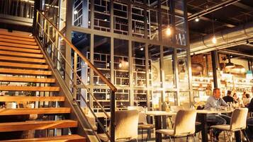 Un intérieur moderne avec un escalier menant à une mezzanine, qui comprend un espace repas avec des tables et des chaises.