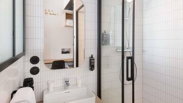 Un bagno moderno con uno specchio grande, un lavandino, una doccia e un portasciugamani.