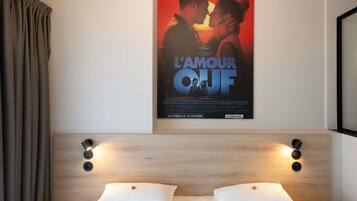 A hotel room with a bed, two bedside tables, and a poster on the wall.