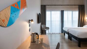 Une chambre d’hôtel avec un bureau en bois, un lit, une chaise et une grande œuvre d’art abstraite accrochée au mur.