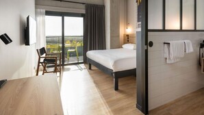 A hotel room with a bed, a desk, a chair, a balcony with a view, and a telephone. - Ibis Styles Namur (Namur)