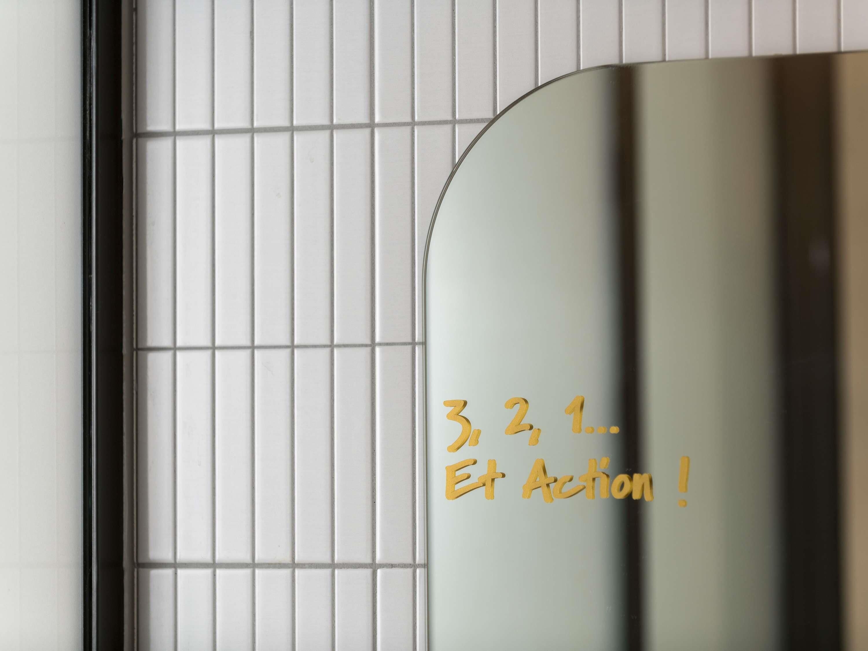 A tiled wall with a mirror reflecting text.