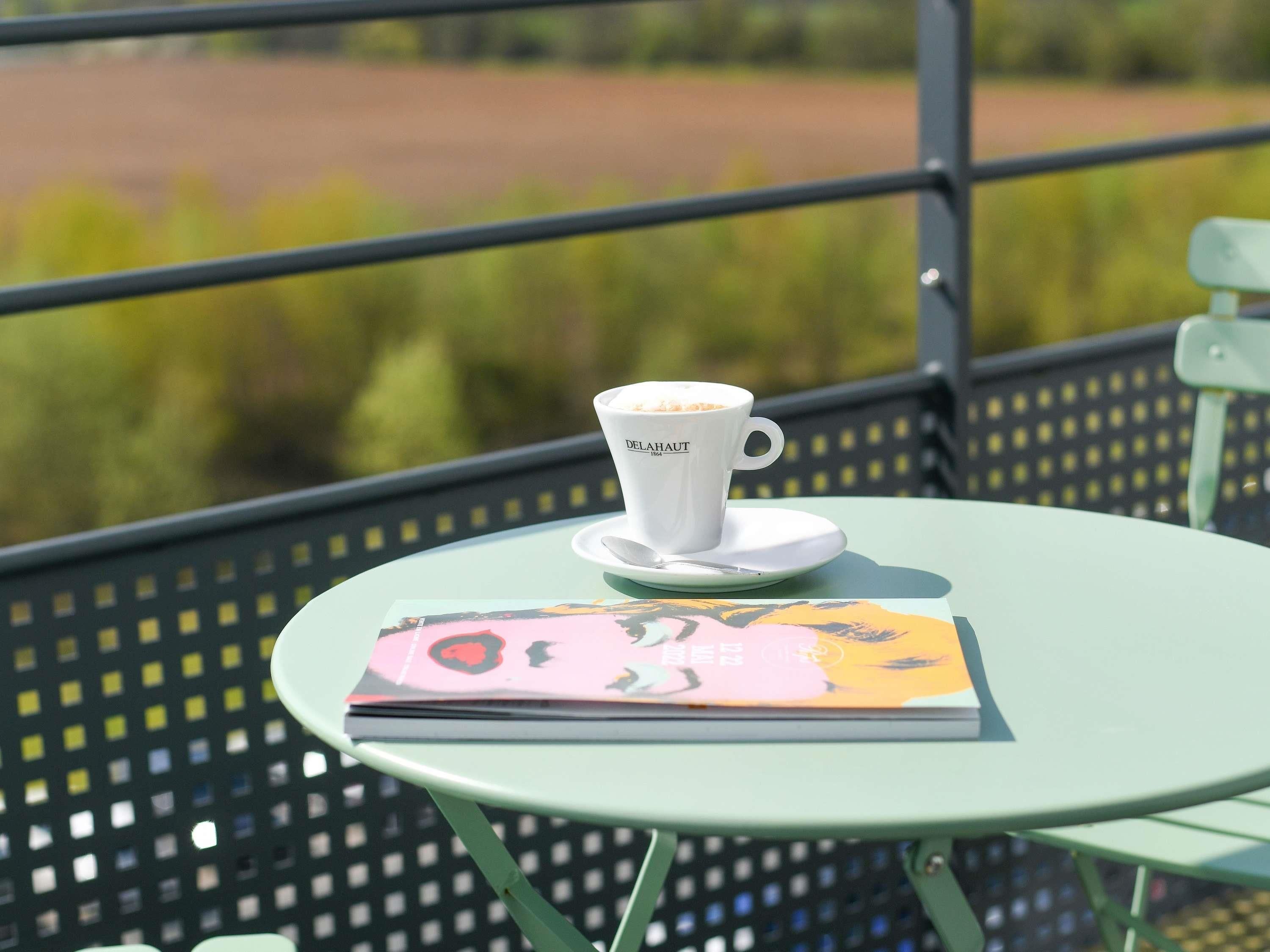 A table with a cup of coffee and a book on it.