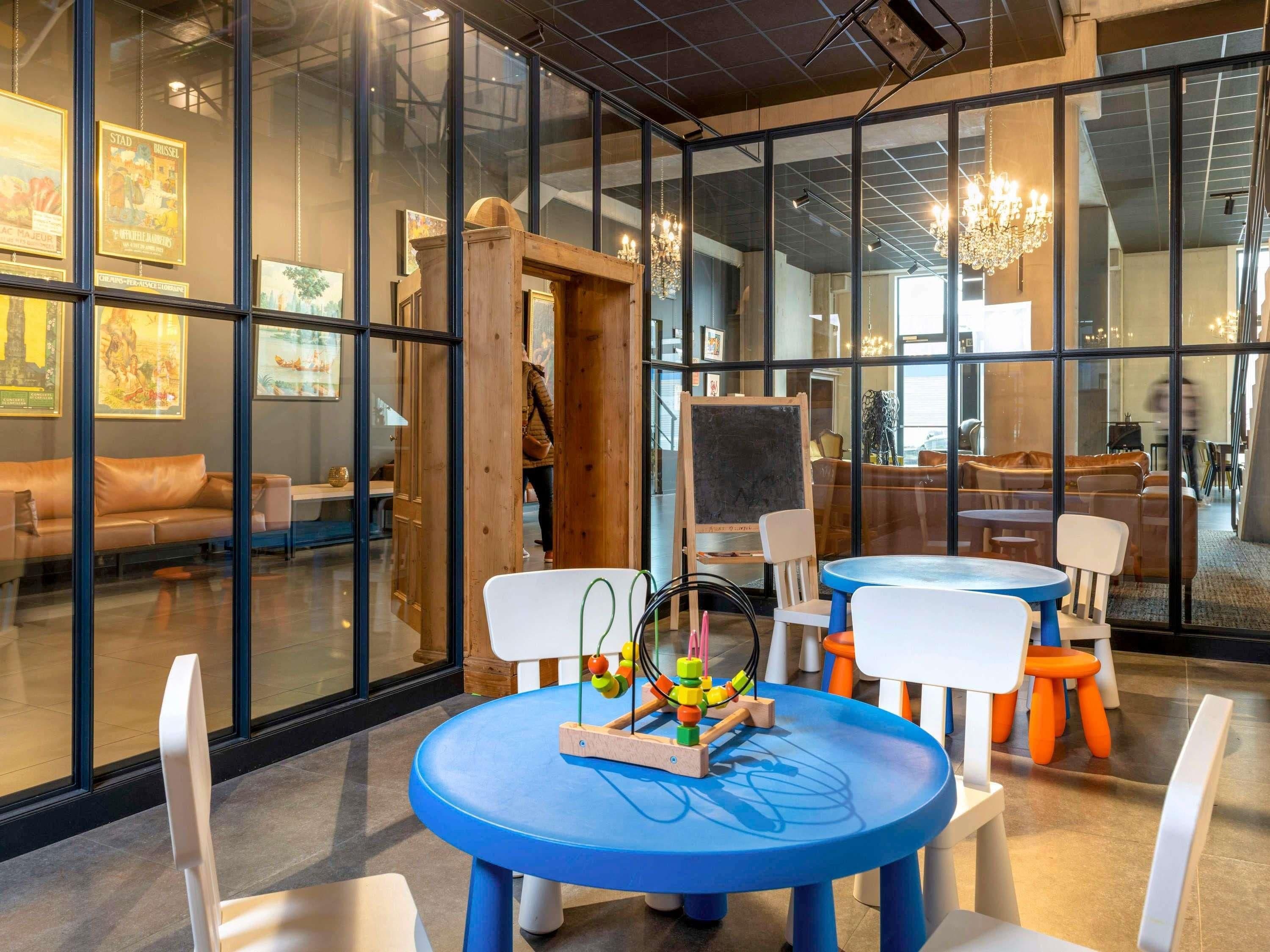 Un interior moderno con paredes de vidrio, muebles de madera y un área de juegos infantil con una mesa de juguetes.