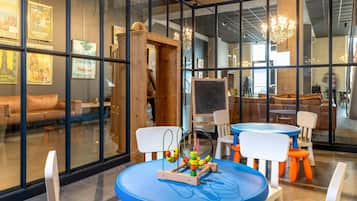 Un interior moderno con paredes de vidrio, muebles de madera y un área de juegos infantil con una mesa de juguetes.