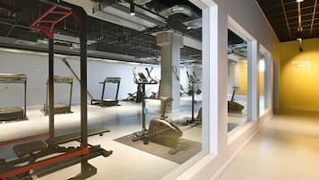 Una palestra con diverse attrezzature per esercizi, una bilancia e un cartello che indica una sala fitness.