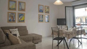 Een woonkamer met een bank, eettafel, stoelen en kunst aan de muren.
