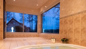 A spa area with a hot tub, large windows, and a view of a house.