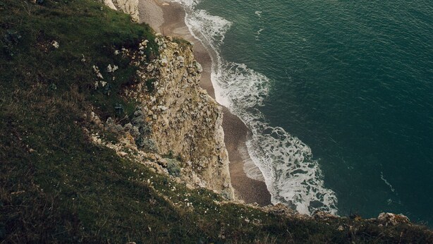 A coastal town with a prominent cliff and an arch formation.