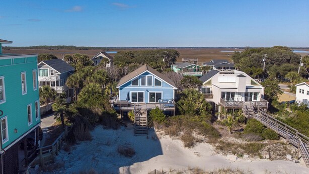 A beachfront property with multiple houses, a sandy beach, and a clear view of the ocean.