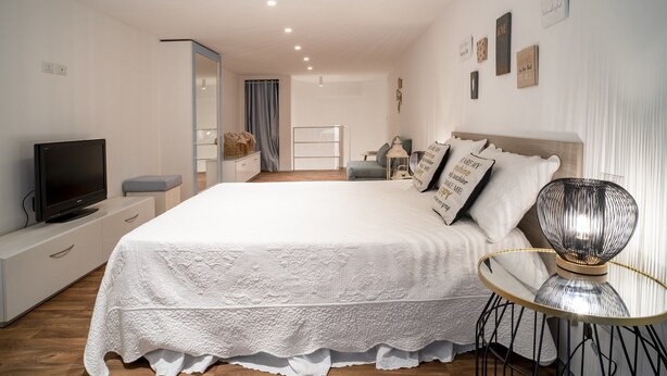 A modern bedroom with a large bed, bedside tables, a TV, and decorative wall art.