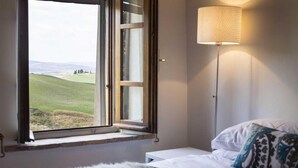 A bedroom with a large window, a bedside lamp, and a fluffy white rug. - VILLA CANTUCCI (Lajatico)