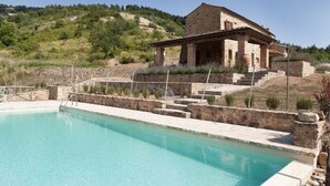 A stone building with a pool, surrounded by a stone wall and steps leading up to it. - VILLA CANTUCCI (Lajatico)