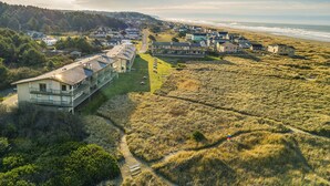 Vue aérienne d’un quartier résidentiel situé sur la côte, avec des maisons, une plage et une route menant à la plage.