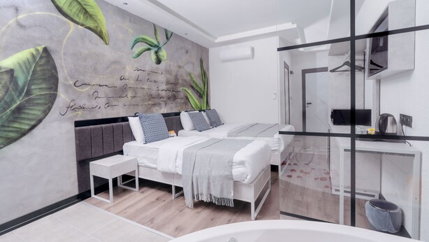 Een moderne slaapkamer met een groot bed, een klein nachtkastje, een ingebouwde televisie en een groot raam.