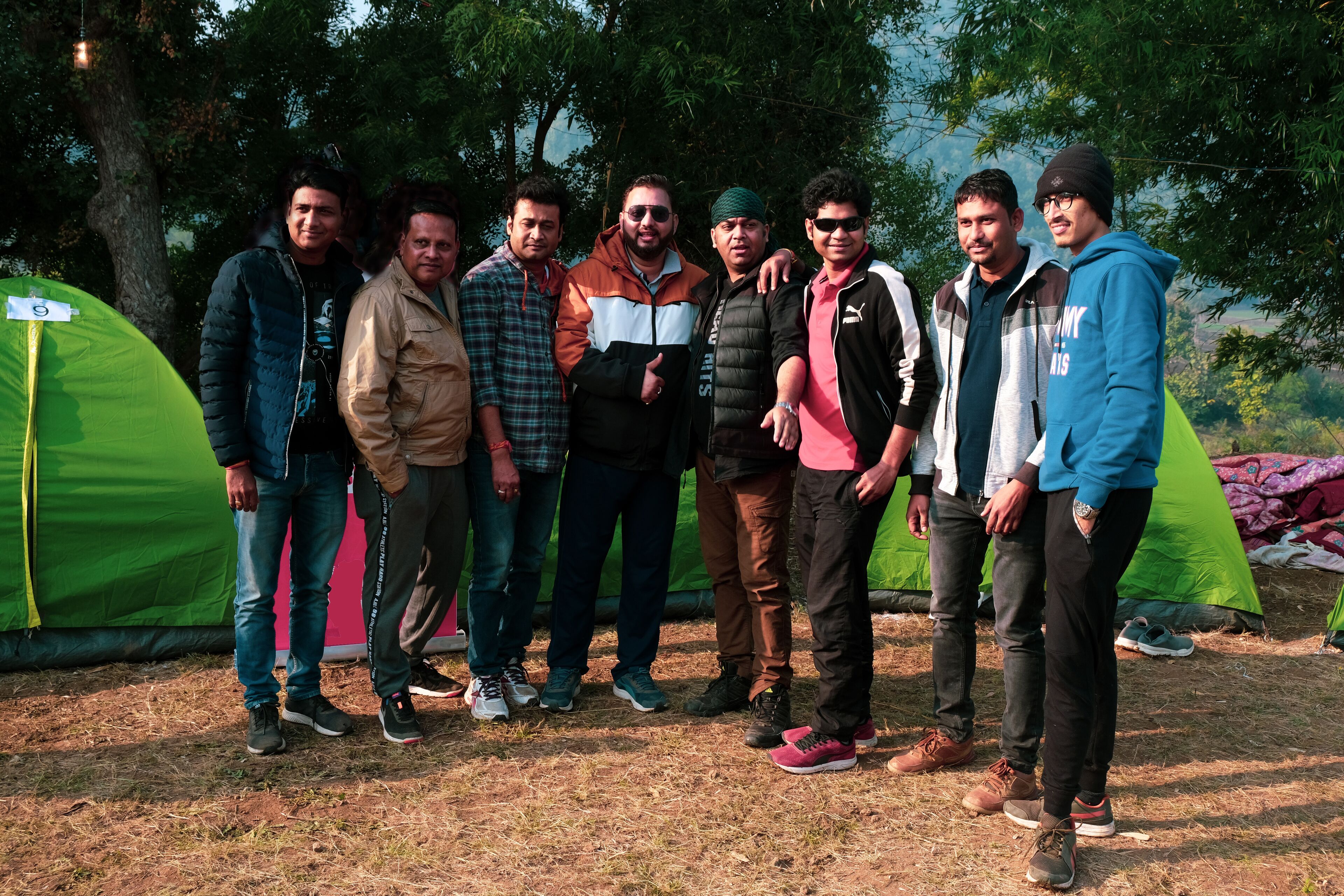 A group of people standing in front of tents in an outdoor setting.