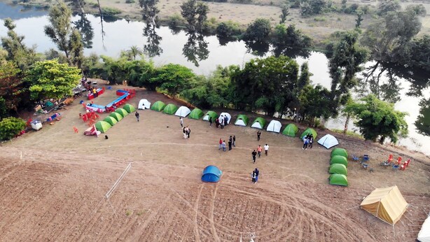 Un camping con tiendas de campaña y una zona de comedor junto a un lago.