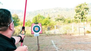 Una persona apuntando a un blanco de tiro con arco al aire libre.