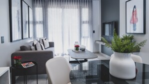 Ein modernes Wohnzimmer mit einer Couch, einem Couchtisch und einem großen Fenster mit transparenten Vorhängen.