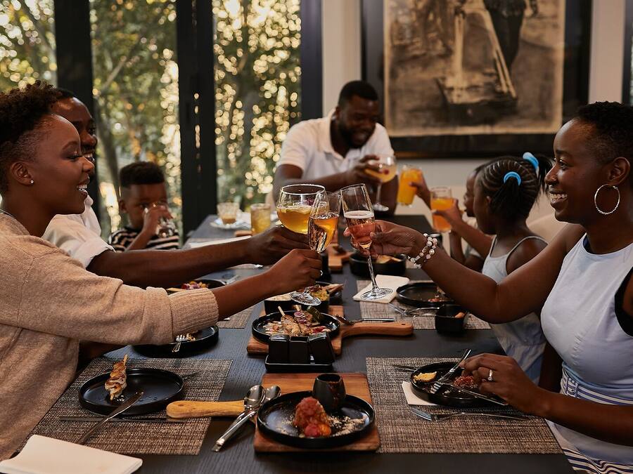 Un grupo de personas cenando en una mesa con diversos platos y bebidas.