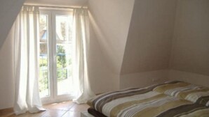 Un dormitorio con cama, ventana con cortinas y vistas a zonas verdes.