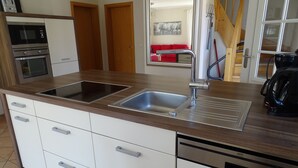 Una cocina moderna con dos lavamanos de acero inoxidable, lavavajillas empotrado y microondas.