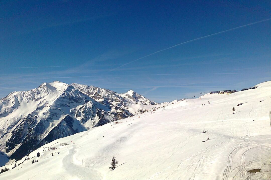 A snow-covered mountain landscape with ski trails and a clear sky.