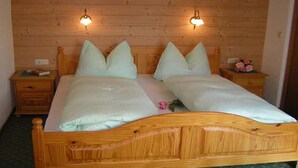 A wooden bed with two nightstands, each with a lamp and a small table. - Haus Guenther, vacation apartment for families, couples or singles. (Aschau im Zillertal)