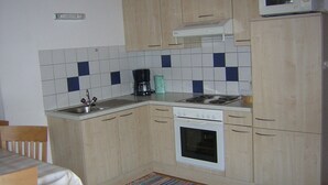 A compact kitchen with a microwave, stove, and sink. - Haus Guenther, vacation apartment for families, couples or singles. (Aschau im Zillertal)
