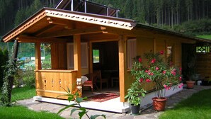 A wooden cabin with a covered porch, stone pathway, and potted plants. - Haus Guenther, vacation apartment for families, couples or singles. (Aschau im Zillertal)