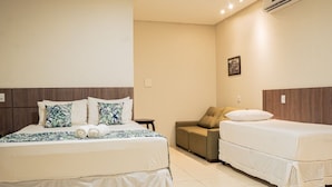 Una habitación de hotel con una cama grande, una cama más pequeña, un sofá y una mesita.
