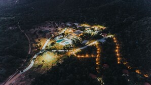 Vista aérea de un complejo turístico con piscina, varias construcciones y senderos bien iluminados.