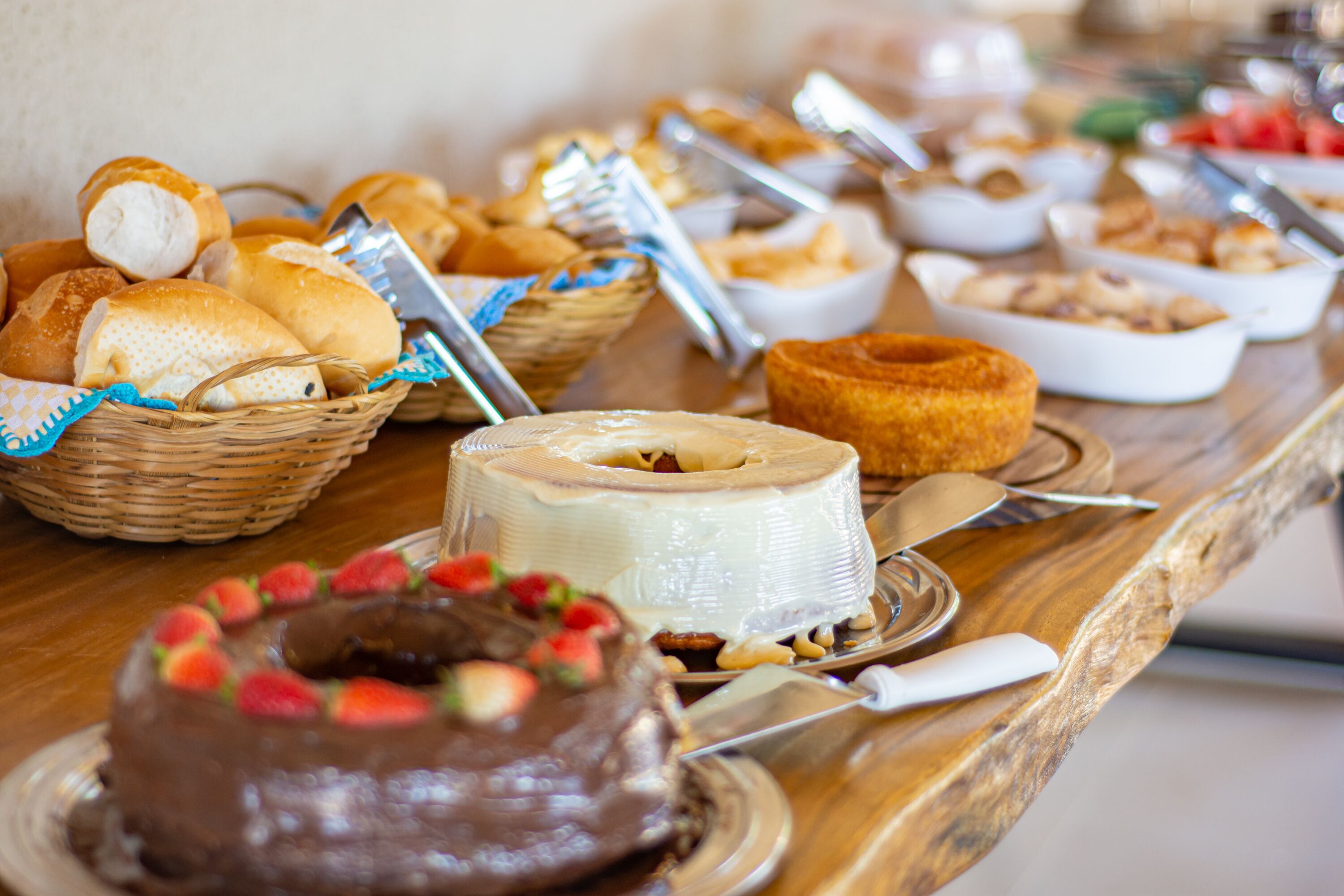 Un buffet con diversi prodotti da forno, tra cui pane, pasticcini e una torta al cioccolato con fragole.