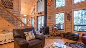 A log cabin interior with a fireplace, leather furniture, and large windows. - Third night free on stays before 9/8/26 (Rhododendron)