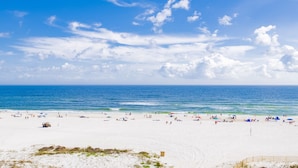 Una extensa playa de arena con cielo azul despejado y océano.