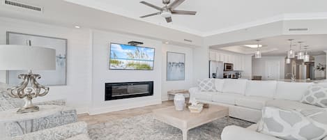 A spacious living room with a fireplace, a television, and a ceiling fan.
