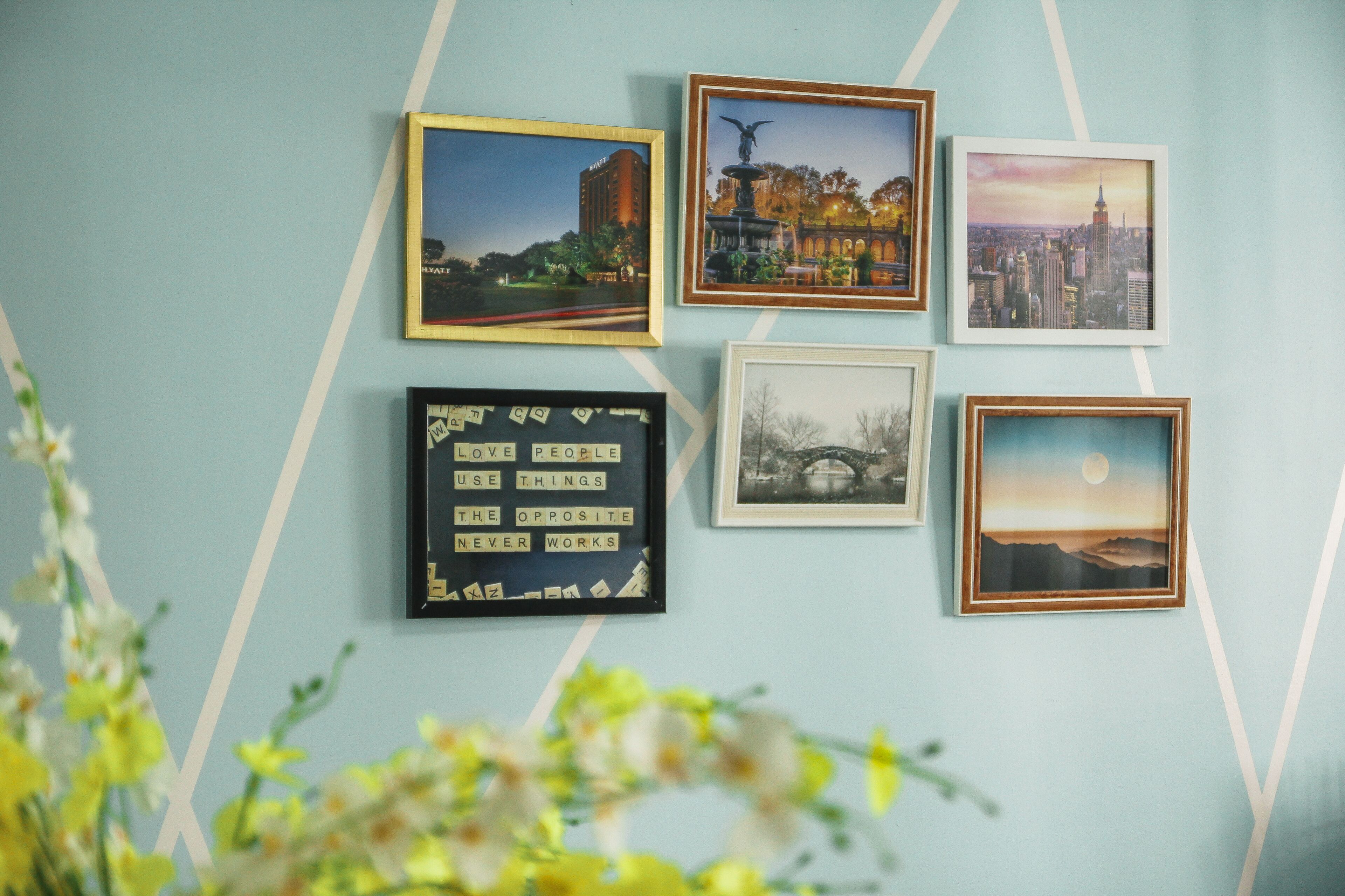 A wall with framed pictures including a cityscape, a bridge, and a quote.