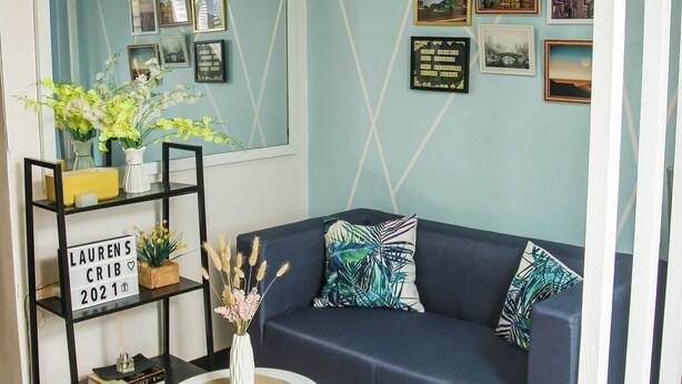Een woonkamer met een blauwe bank, een witte salontafel en een zwarte boekenkast.