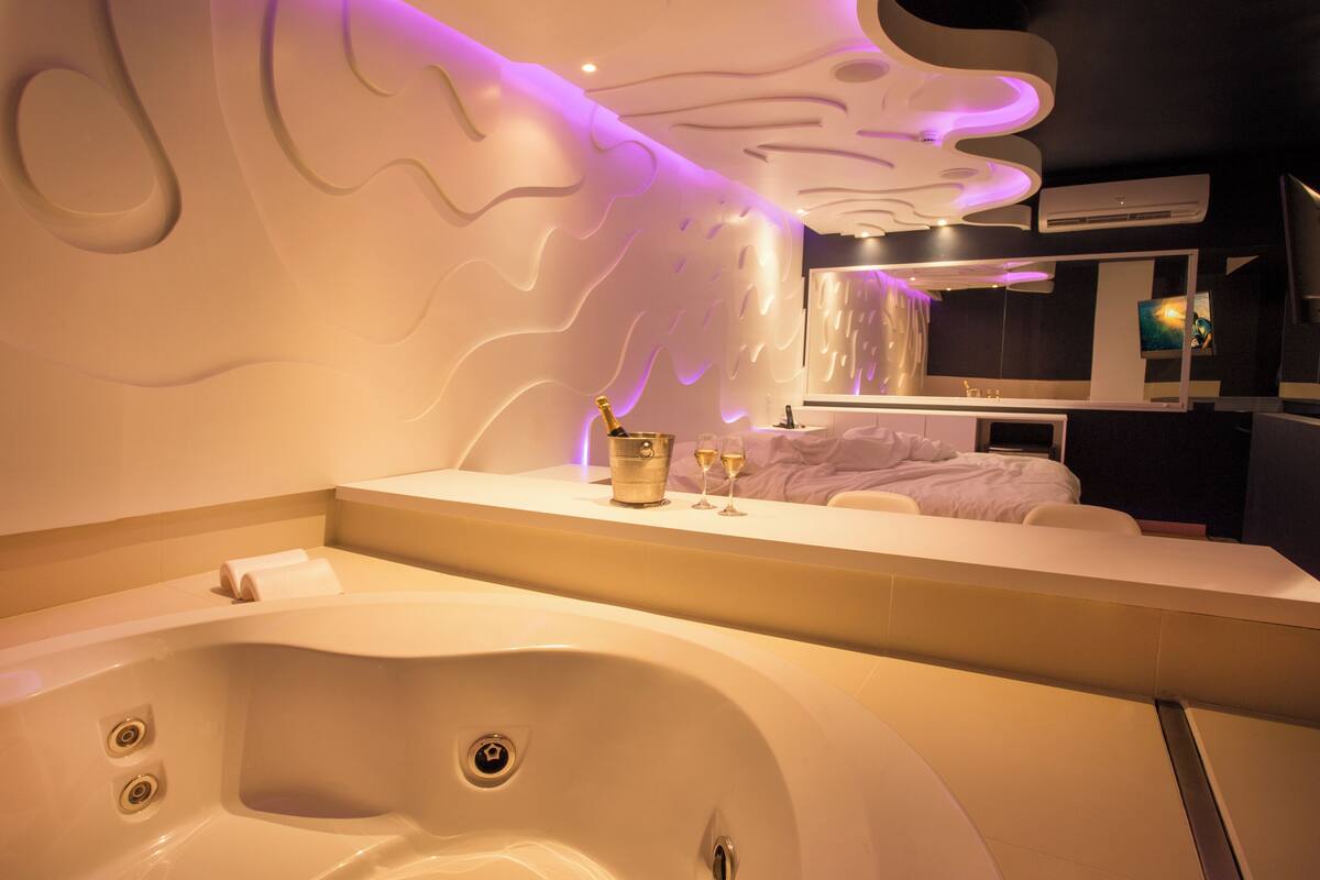 Une salle de bain moderne avec une grande baignoire, un meuble-lavabo avec un miroir et un climatiseur fixé au mur.