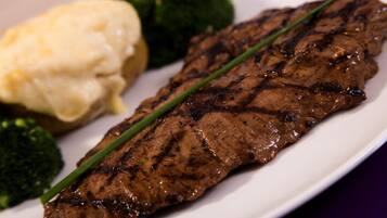 A grilled steak with a garnish of chives, accompanied by a side of mashed potatoes and steamed broccoli.
