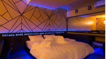 Una habitación de hotel con una pared de diseño geométrico, una cama bien hecha y un minibar.