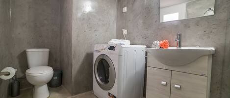 A bathroom with a toilet, washing machine, and sink.