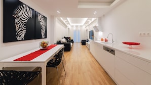 A modern kitchen with white cabinets, a red bowl on the counter, and a zebra artwork on the wall. - D9 center of Glyfada (Glyfada)