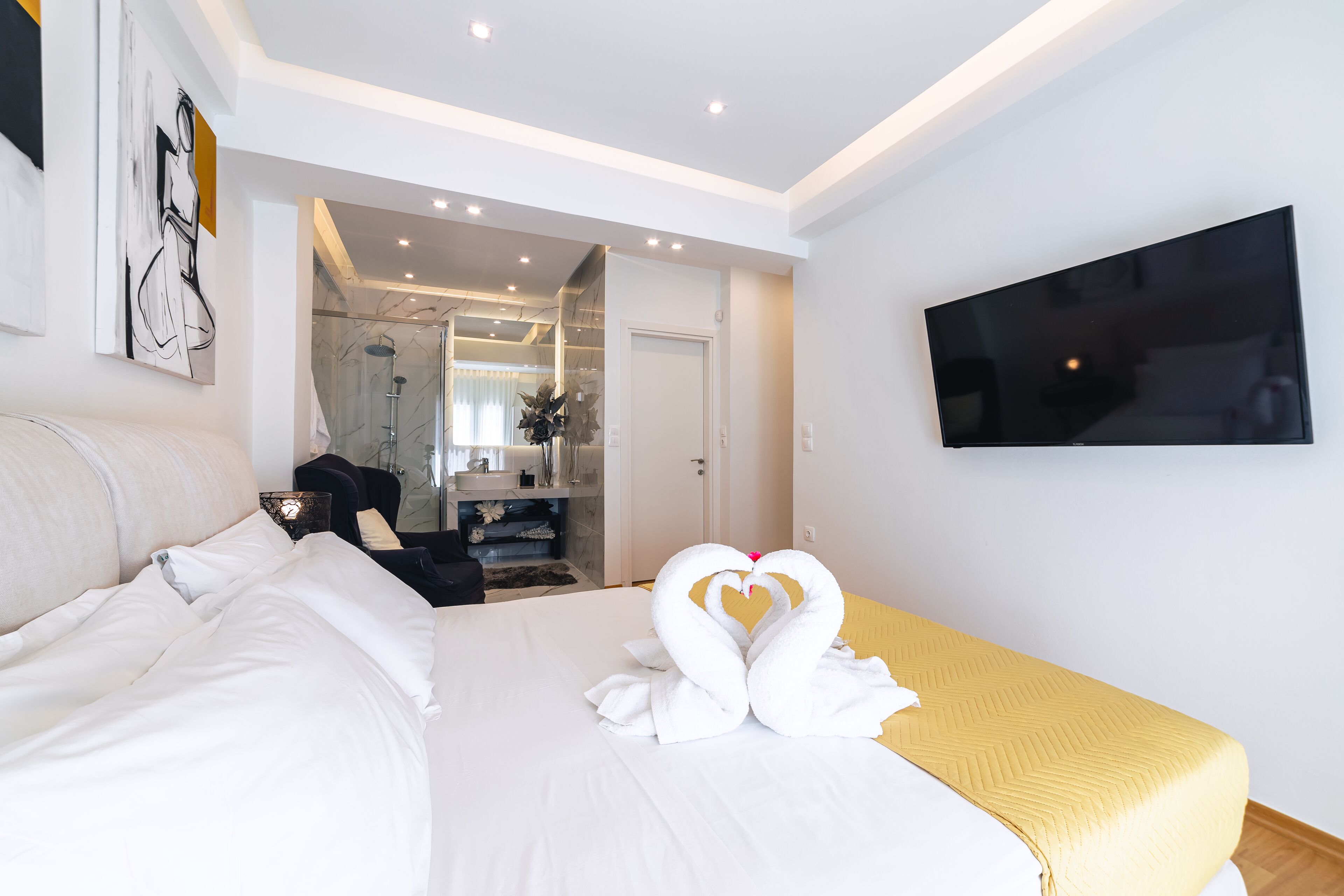 A hotel room with a bed, a TV, and a bathroom visible through an open door.