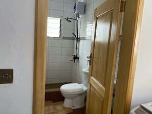 A bathroom with a toilet, a shower, and a towel rack.