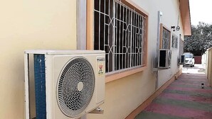 Un equipo de aire acondicionado y una ventana con rejas en la fachada de un edificio.