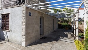 Ein Gebäude mit einer Sandsteinfassade, einem Balkon mit weißem Geländer und einem überdachten Außenbereich mit einer Pergola.