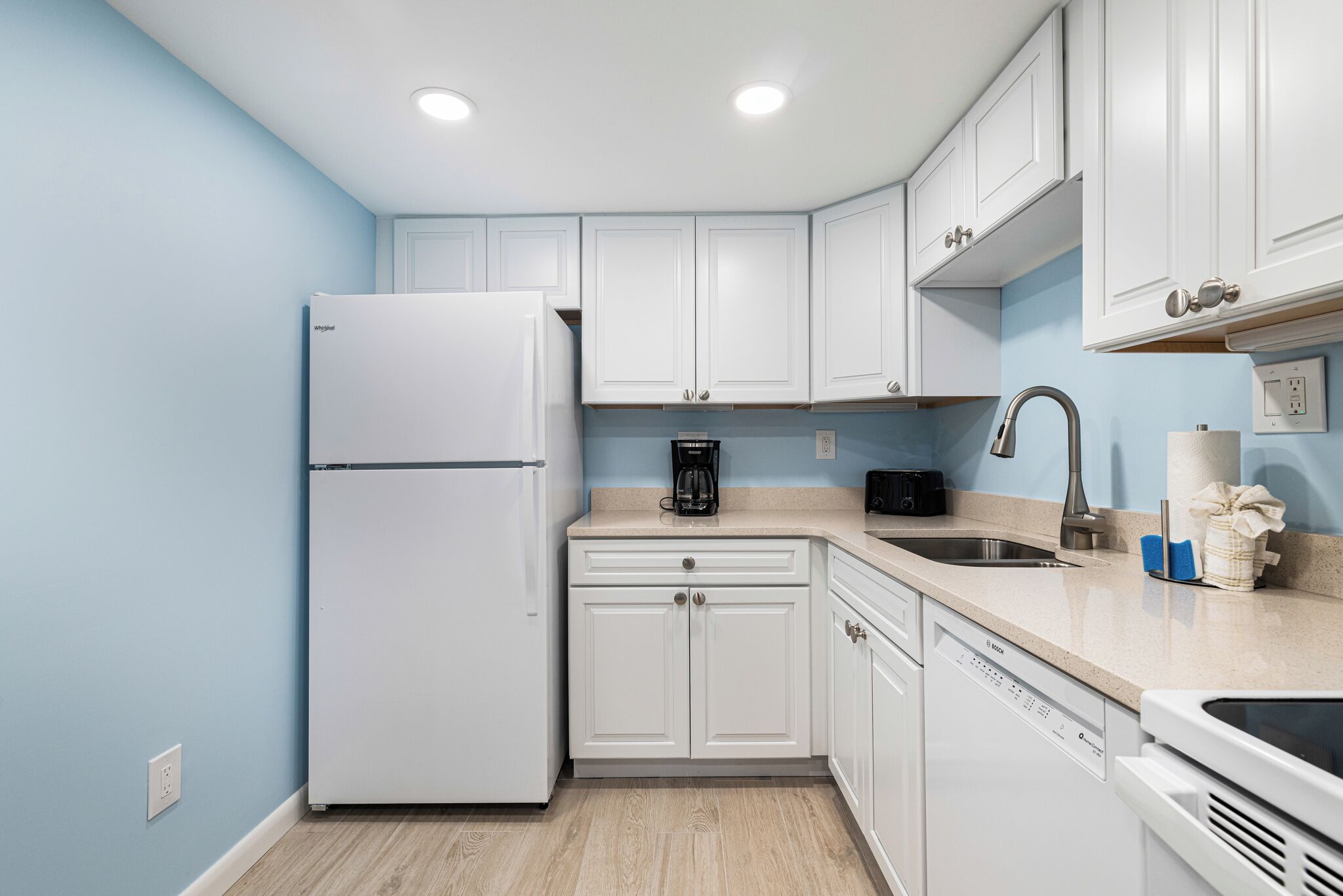 A modern kitchen with white cabinets, a stainless steel sink, and a dishwasher.