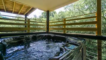 Relax in a hot tub surrounded by lush greenery and a sturdy wooden deck.